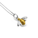 Silver and gold bee pendant on a chain against a white background