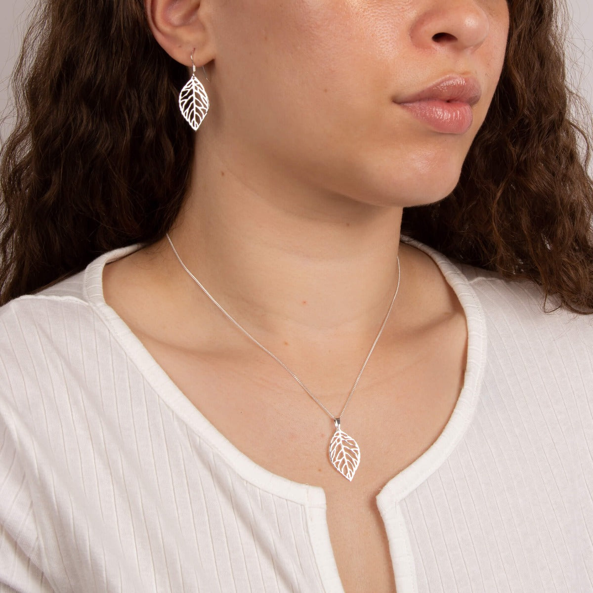 Model wearing cut out leaf pendant in recycled sterling silver
