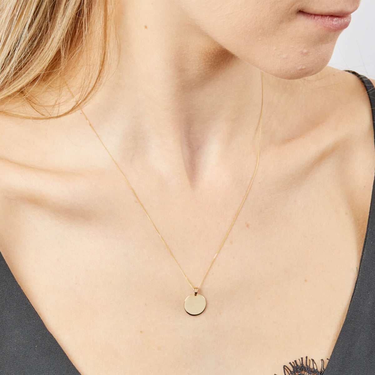 Close-up of plain gold disc pendant