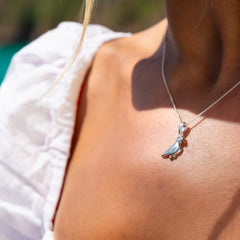 Close up of a woman wearing a silver puffin pendant necklace with rose gold details on the beak.