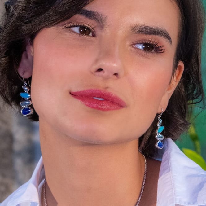 A woman with dark hair wearing Silver Origins turquoise and lapis pebble drop earrings, looking to the side.