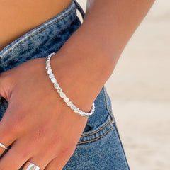 A person wearing the silver pebble bangle on their wrist. Their hand is in the pocket of their denim jeans.