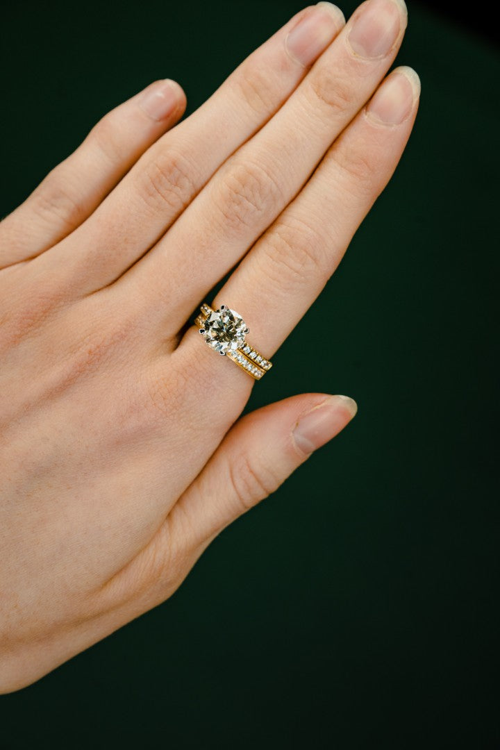 Hand wearing a diamond ring on a dark background