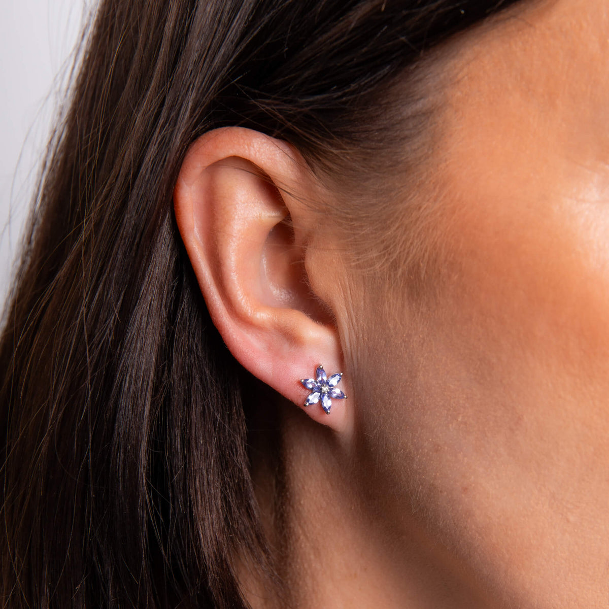 Model wearing tanzanite and diamond flower earrings in 9ct white gold