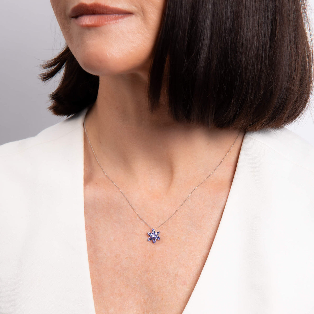 Model wearing tanzanite and diamond flower pendant in 9ct white gold
