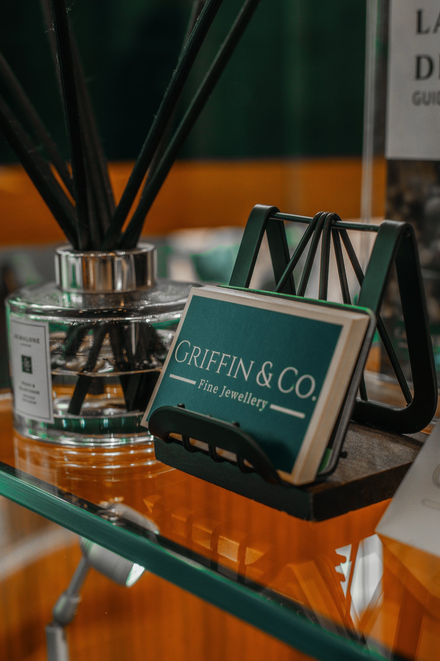 Jewellery display stand with 'Griffin & Co.' branding next to a glass container with reeds.