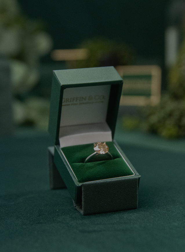 A stunning cushion-cut lab-grown diamond solitaire engagement ring presented in its signature green Griffin & Co jewellery box. An example of the beautiful, ethical engagement rings available online and from our Chichester store.