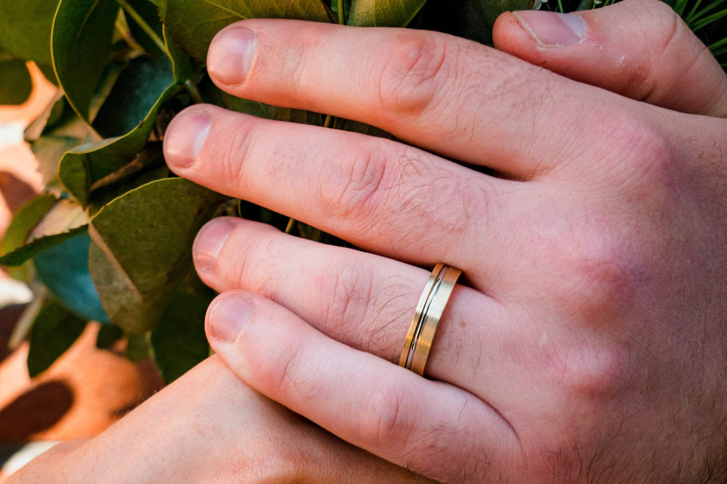 Close-up of hands holding a bouquet with wedding rings on a brick wall background
