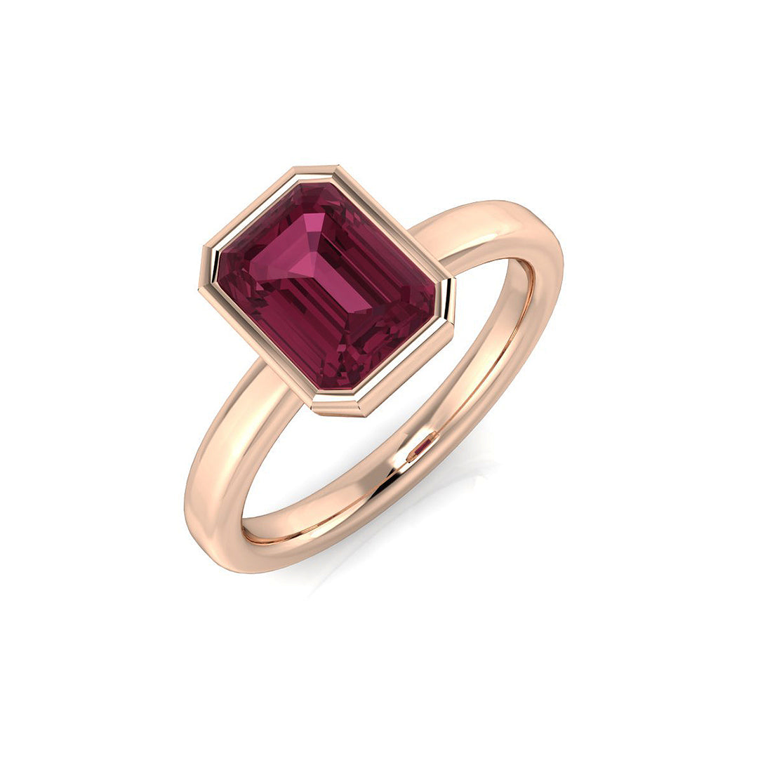 An emerald-cut pink tourmaline solitaire ring with a bezel setting, crafted in 9ct rose gold, on a white background.