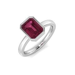An emerald-cut pink tourmaline solitaire ring with a bezel setting, crafted in 9ct white gold, on a white background.