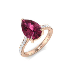 A large pear-cut pink tourmaline engagement ring with a diamond pavé band, crafted in 9ct rose gold, on a white background.