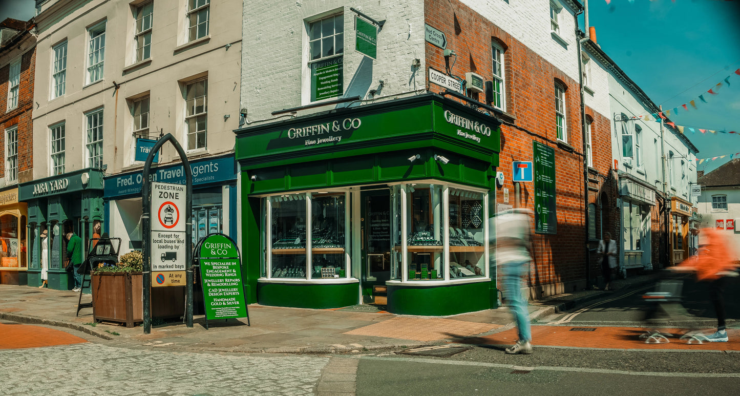 Green storefront with 'Griffith & Co' on a street corner with pedestrians and shops.