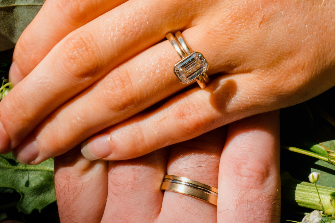 Close-up of hands with wedding rings on a bouquet of flowers.