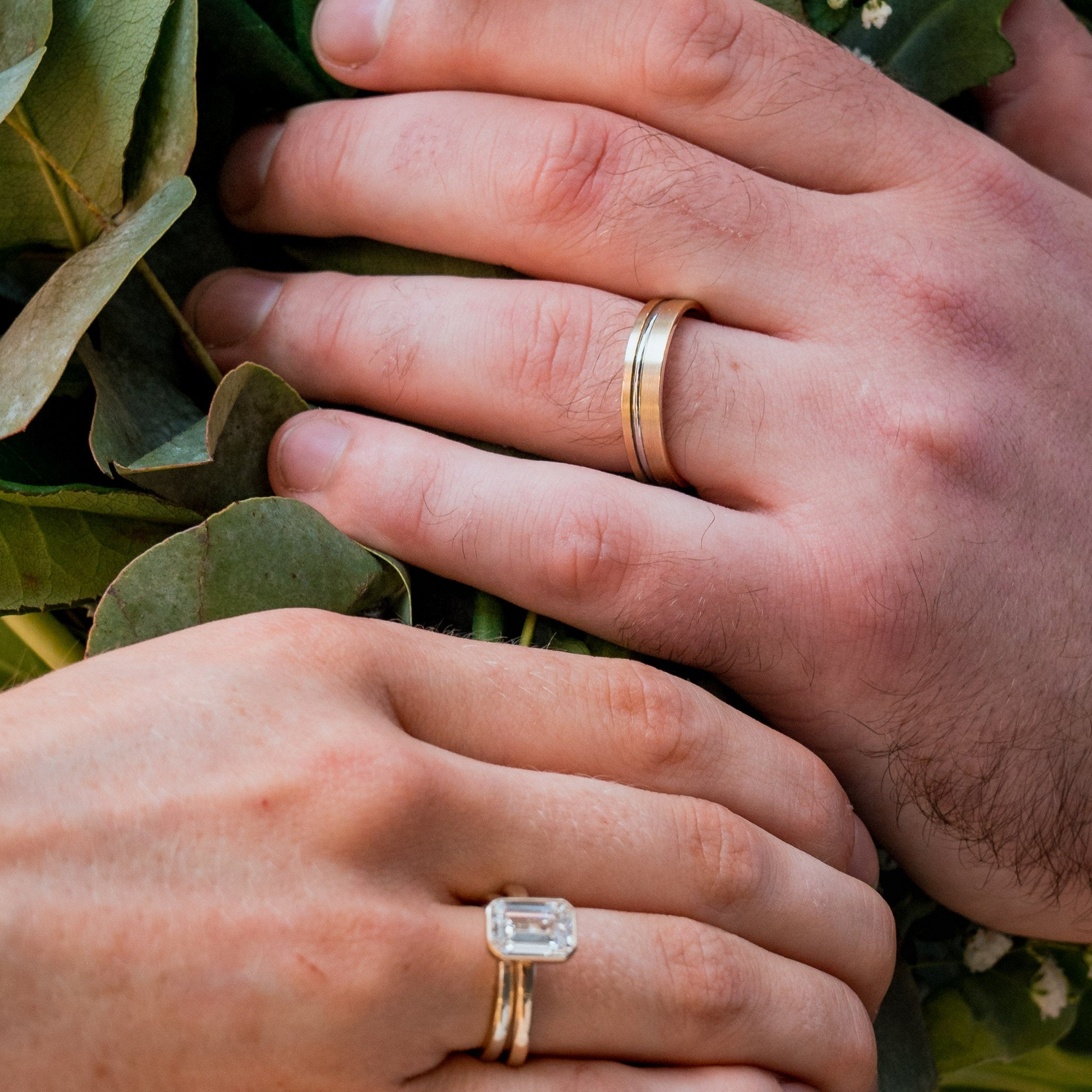 Two hands holding a bouquet with wedding rings on a blurred background