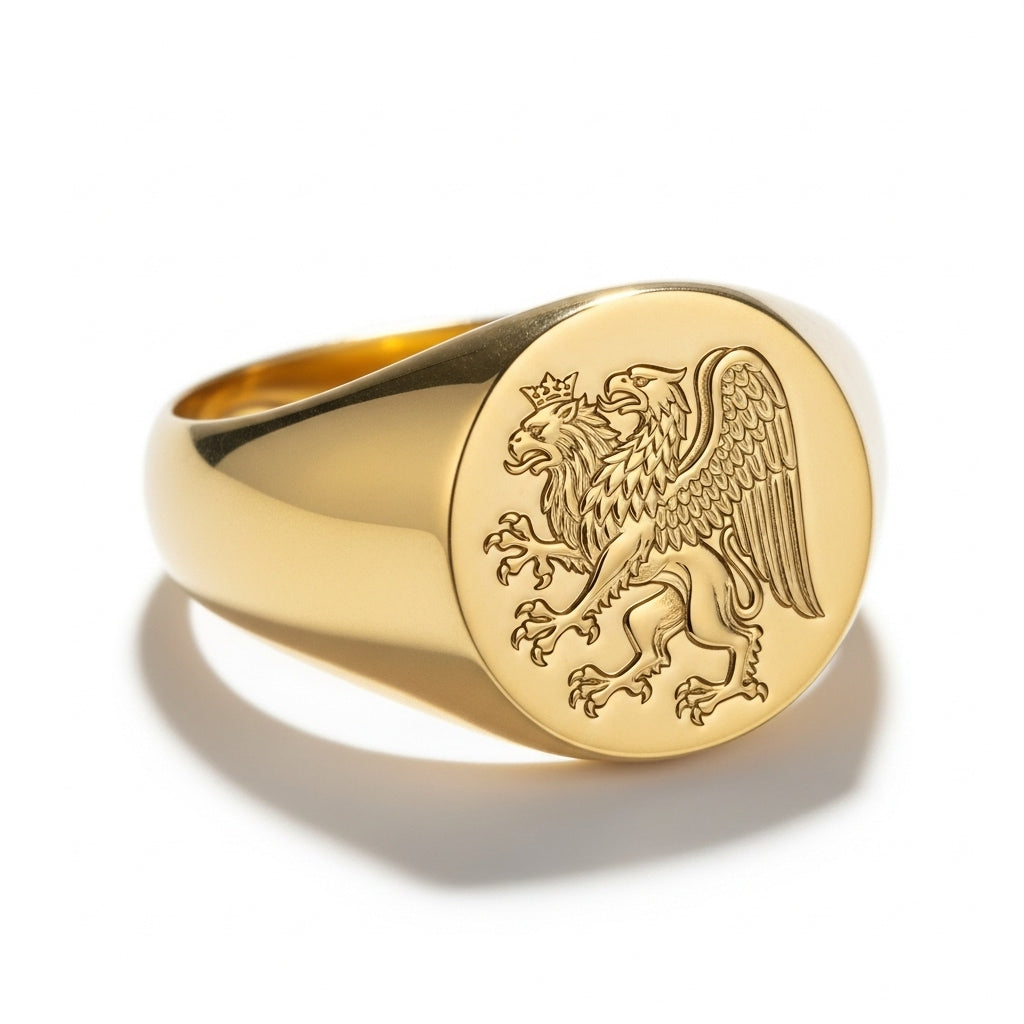 A detailed close-up of a gold signet ring with a Griffin crest. The griffin, a mythological creature with the head and wings of an eagle and the body of a lion, is intricately carved into the face of the ring. The ring is a classic, polished gold design, and is displayed on a crisp white background with a soft shadow.
