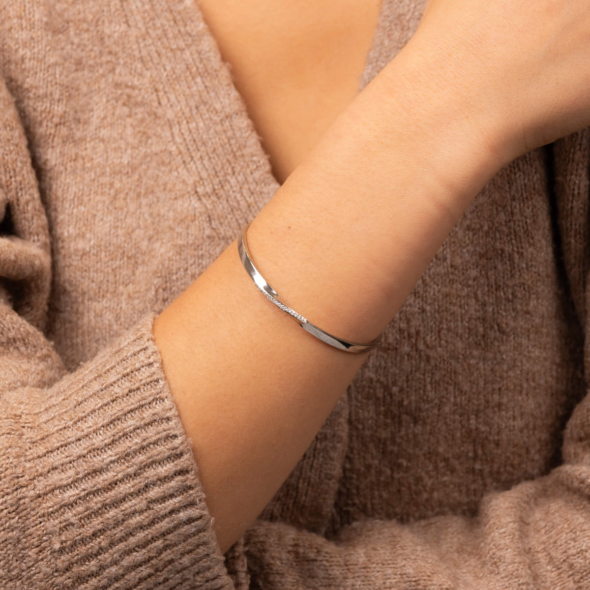 Model wearing twist open bangle with cubic zirconia