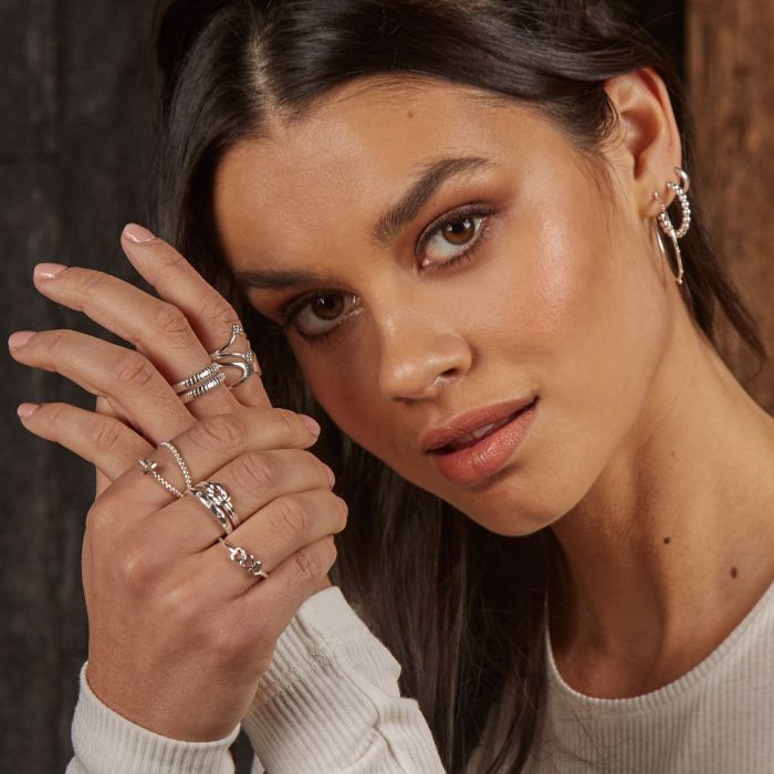 Woman wearing multiple rings on her hand with a neutral background