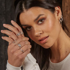 Woman wearing multiple rings on her hand with a neutral background