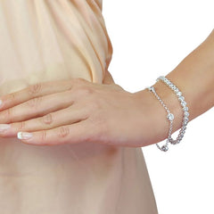 Silver bracelet on a wrist with a plain background