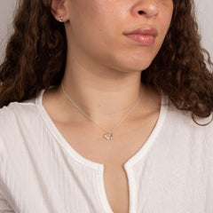 Close-up of a person wearing a delicate necklace with a heart pendant.
