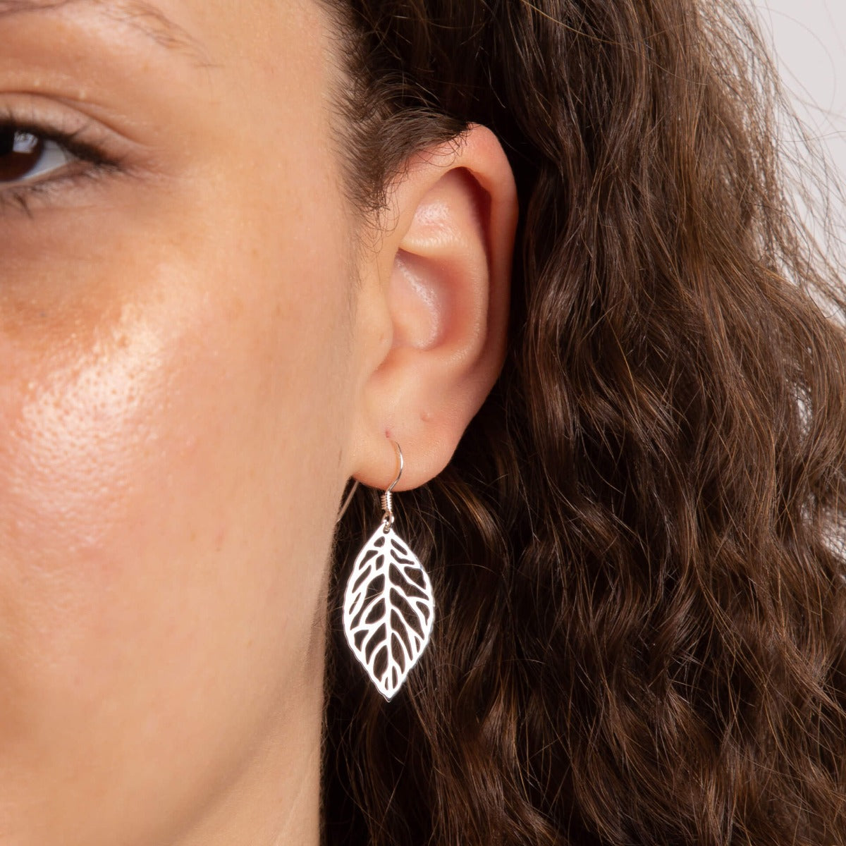 Model wearing cut out leaf drop earrings in recycled sterling silver