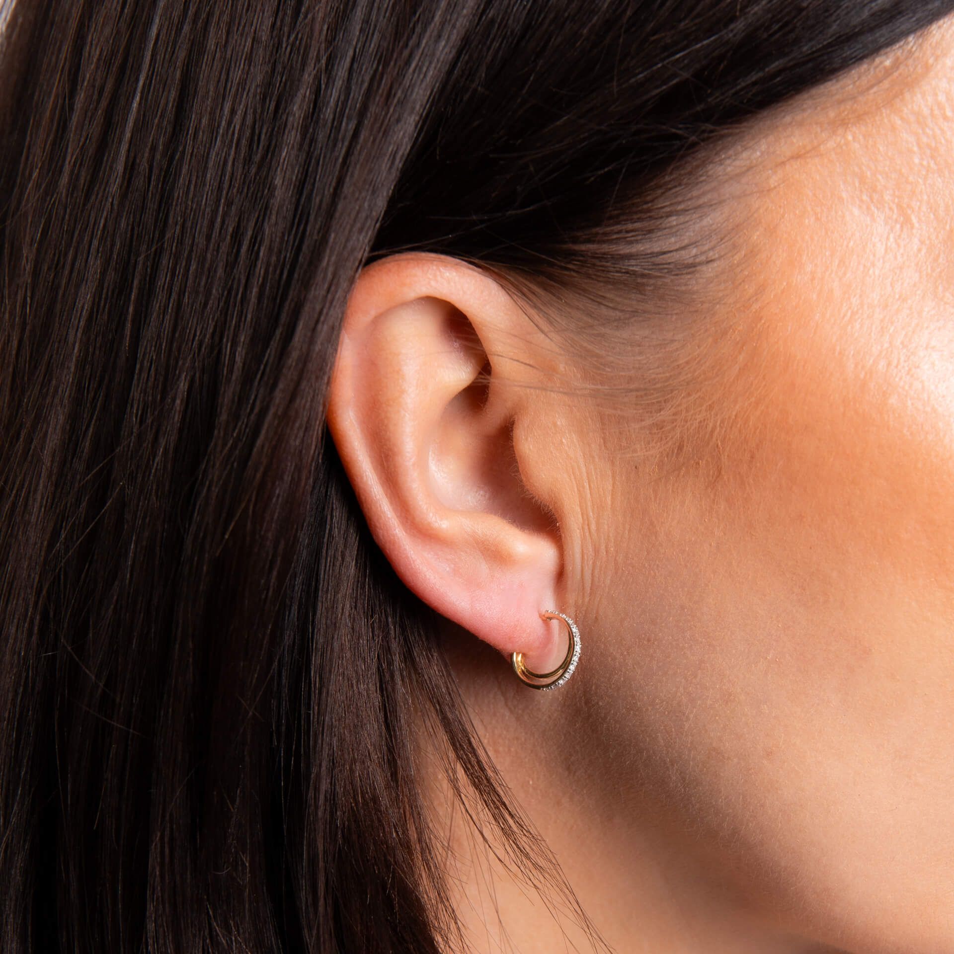 A close-up of a woman's ear wearing the diamond double hoop earrings, showing the elegant twin hoop design.