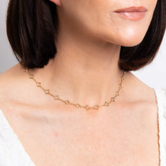 A close-up of a woman's neck wearing the 9ct gold quatrefoil station necklace.