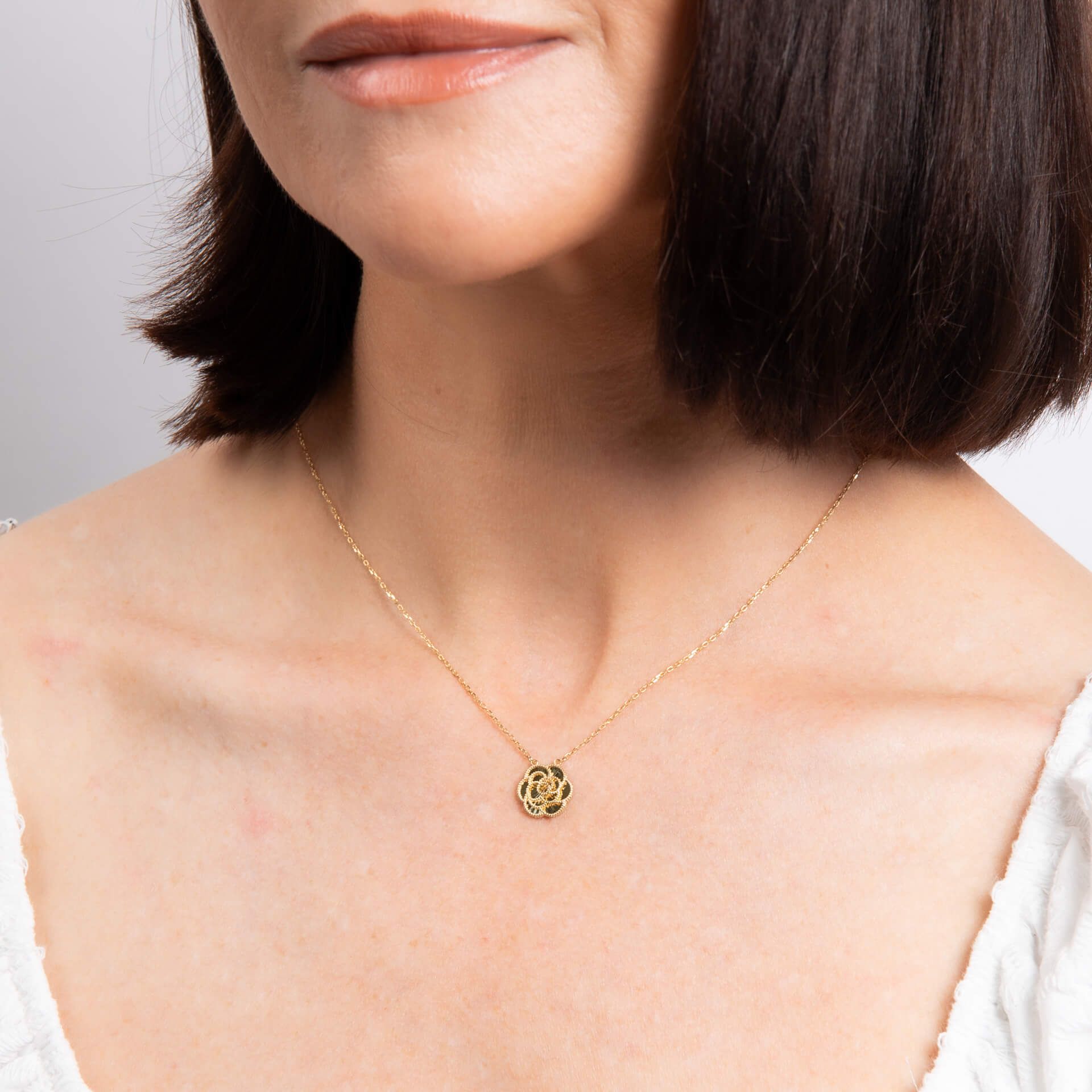 A close-up of a woman's neck wearing the gold English Rose pendant necklace.
