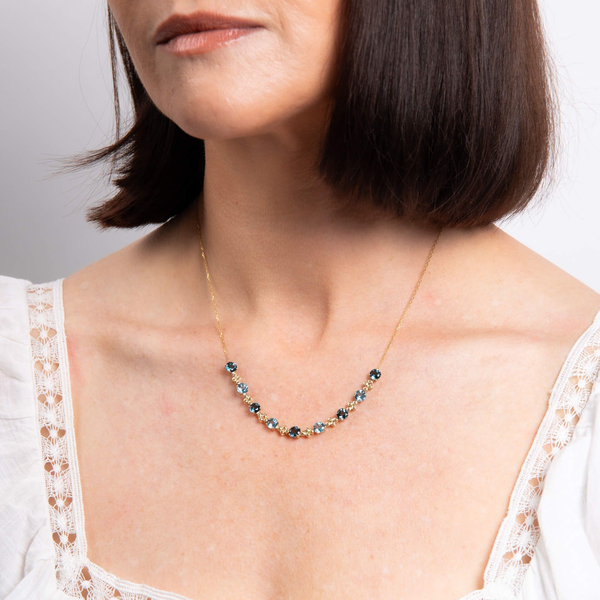 A close-up of a woman's neck wearing the ornate blue topaz necklace.