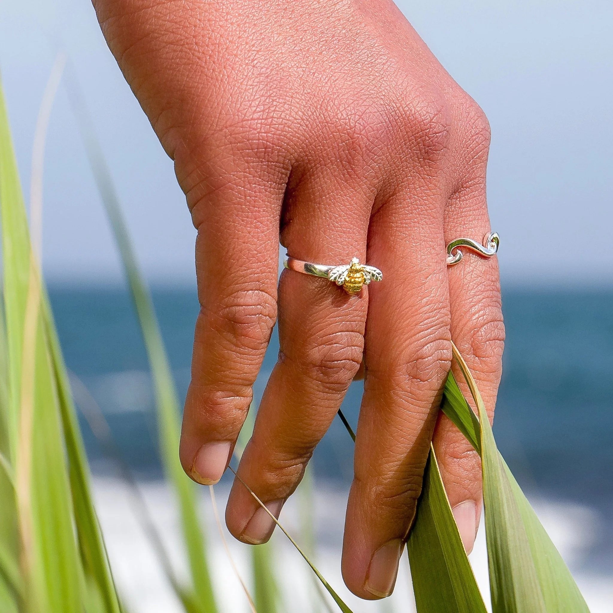 Hand with two rings holding a leaf against a blurred natural background