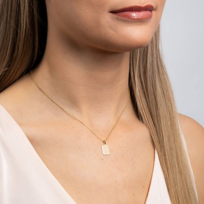 Model wearing rectangular 9ct yellow gold dog tag pendant on chain