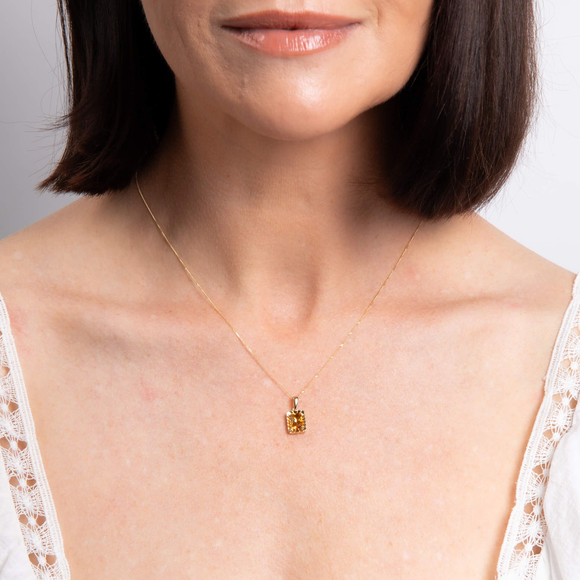 A close-up of a woman's neck wearing the gold citrine octagon pendant on a delicate chain.