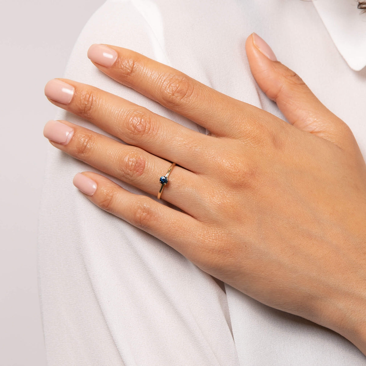 Model wearing round teal sapphire ring on hand