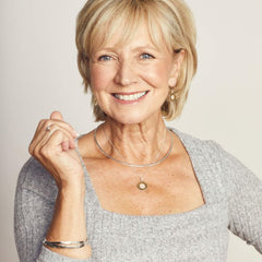 Woman with short blonde hair wearing a gray sweater against a plain background