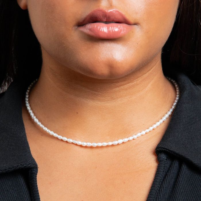 Close-up of a person wearing a pearl necklace with a blurred background
