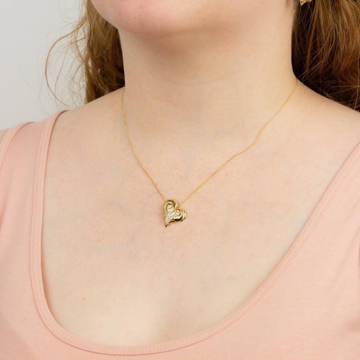 Heart pendant with yellow gold detail worn on chain, recycled silver