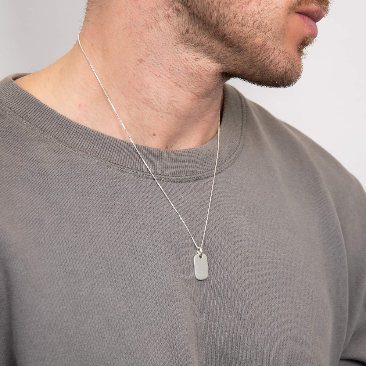 Model wearing rounded rectangle tag pendant on chain