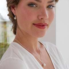 Woman wearing a necklace with a clear pendant against a blurred background