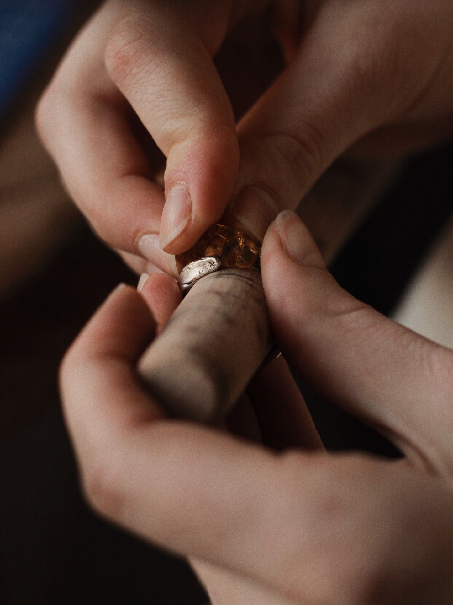 Close-up of hands engraving a signet ring with a blurred background