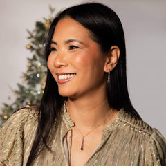 Woman wearing a gold glittery top with a Christmas tree in the background